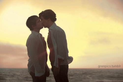 two men kissing each other on the beach