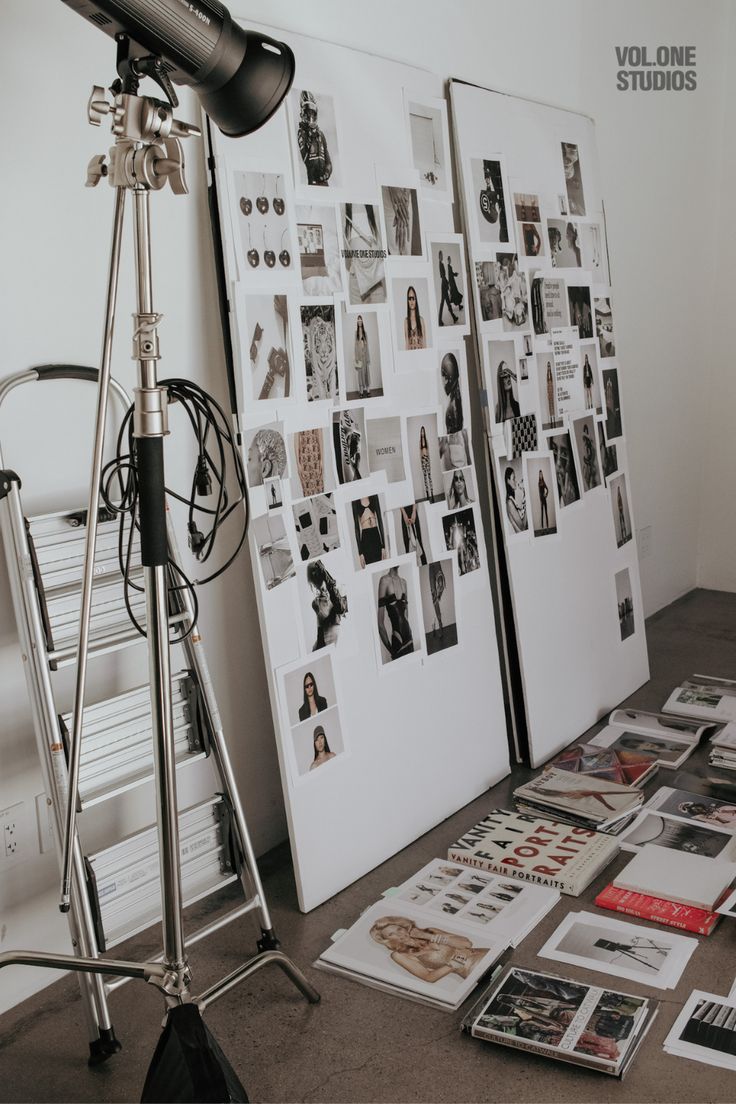 a photo shoot is set up in front of a wall with pictures and lighting equipment