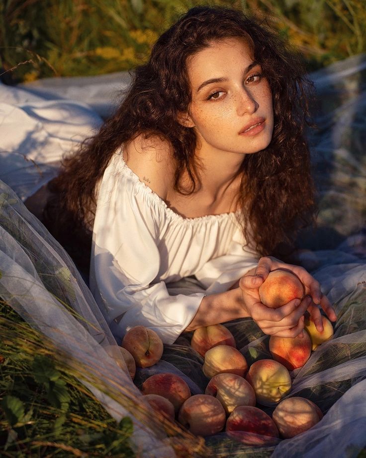 a woman laying on the ground with some fruit in her hands and looking at the camera