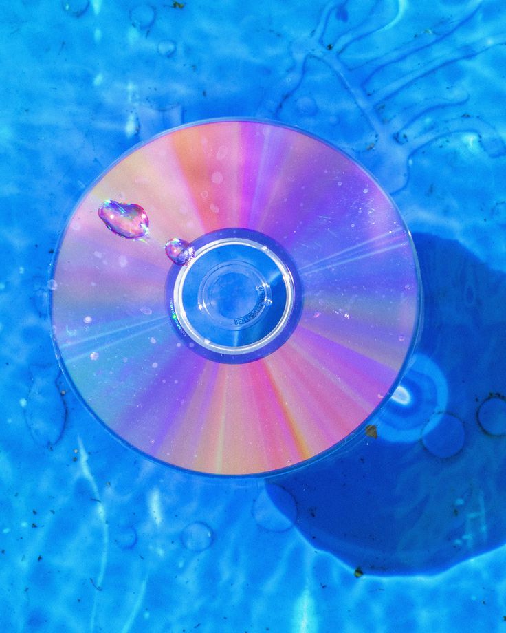 a cd that is sitting in the water on top of some blue material with bubbles around it