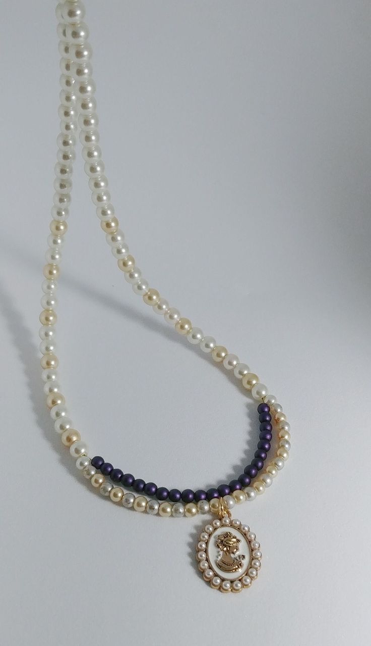 Cameo Pendant Pearl Beaded Necklace, Pearl colored glass beads are accented with a strand of smaller purple beads. Magnet Closure is great for older or disable folks that find clasped jewelry difficult. A gold-colored Cameo pendant completes the piece. 18.5inch strand. Variation in color and length is available. Elegant Gold Pearl Necklace With Colorful Beads, Elegant Double Strand Colorful Beaded Necklaces, Elegant Multi-strand Necklaces With Spacer Beads, Elegant Double Strand Beaded Necklace, Classic Double Strand Beaded Necklaces, Classic Double Strand Beaded Necklace, Elegant Multi-strand Purple Beaded Necklaces, Elegant Multi-strand Pearl Necklace With Colorful Beads, Elegant Purple Multi-strand Beaded Necklaces