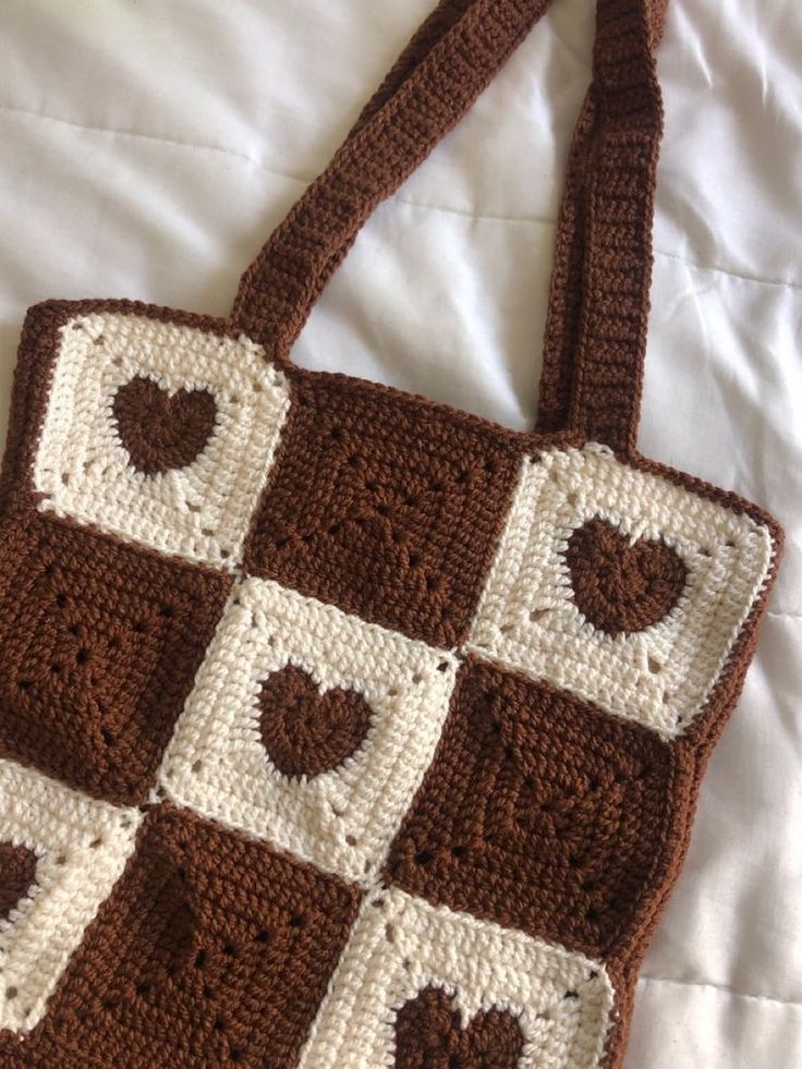 a crocheted brown and white purse on a bed