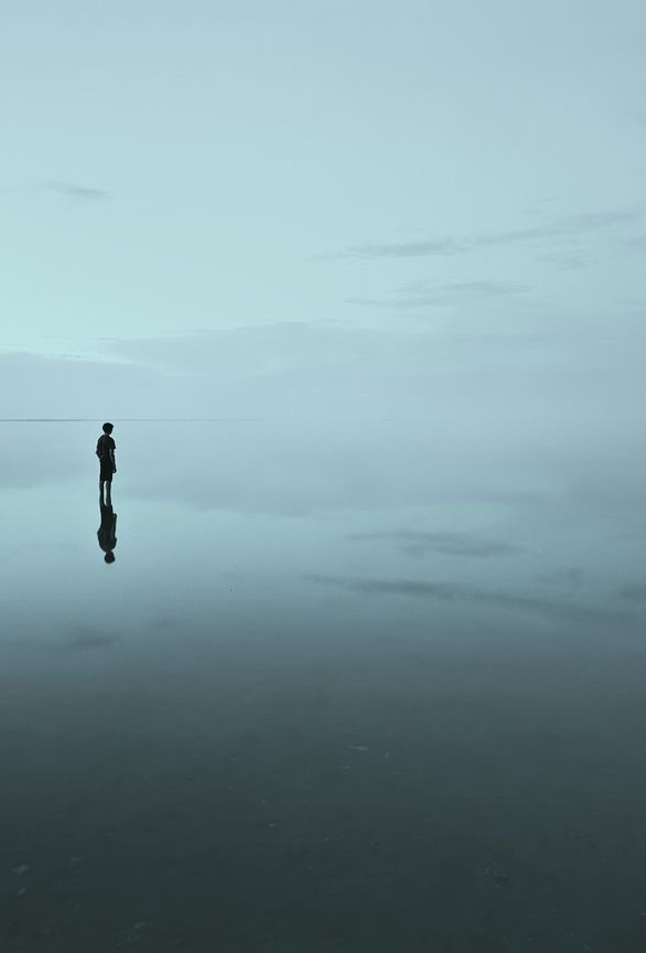 a lone person standing in the water on a foggy day