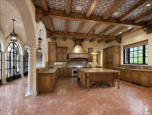 a large kitchen with wooden cabinets and marble counter tops, along with an island in the middle