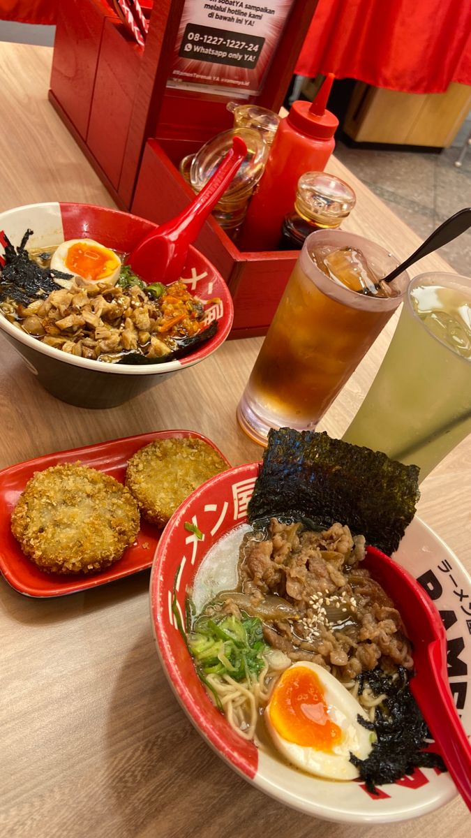 three plates of food on a table with chopsticks and drinks in the background