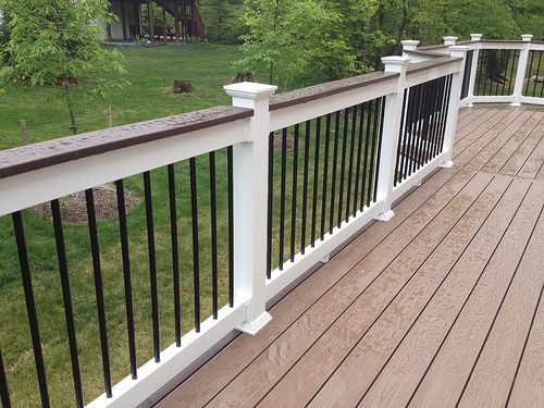 a wooden deck with white railings and black rails