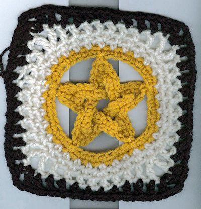 a crocheted square with a yellow and white star in the center on it