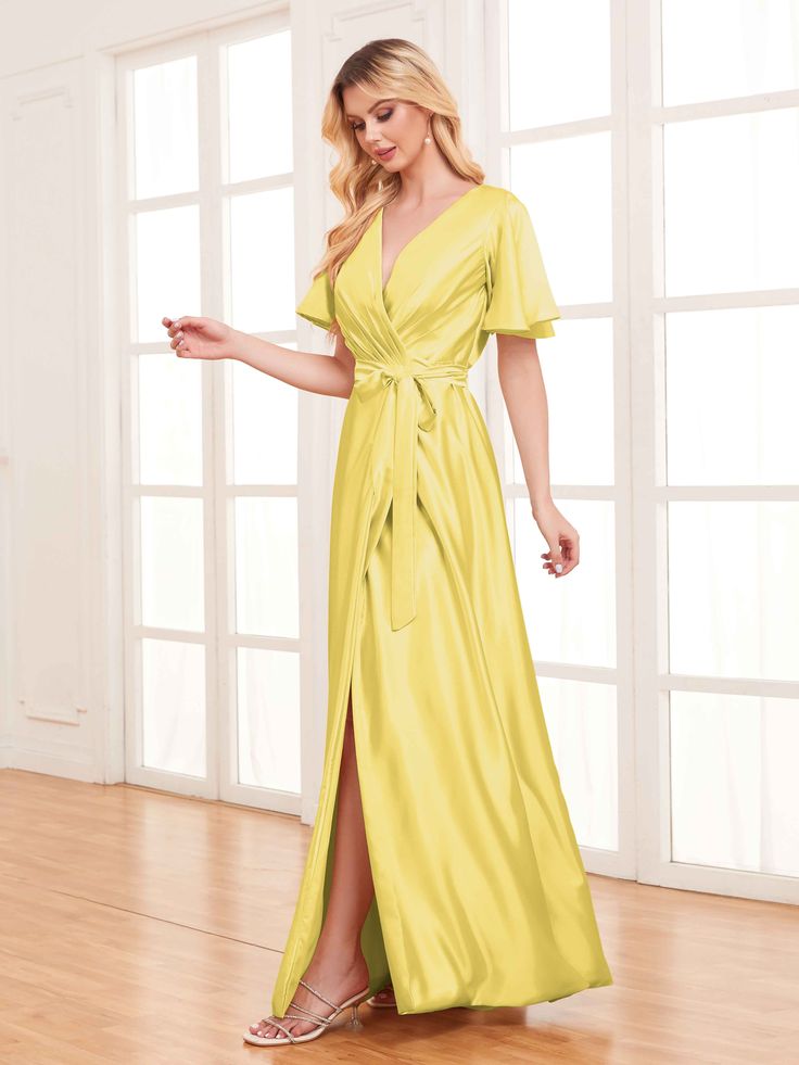 a woman in a yellow dress standing on a wooden floor with her hand out to the side