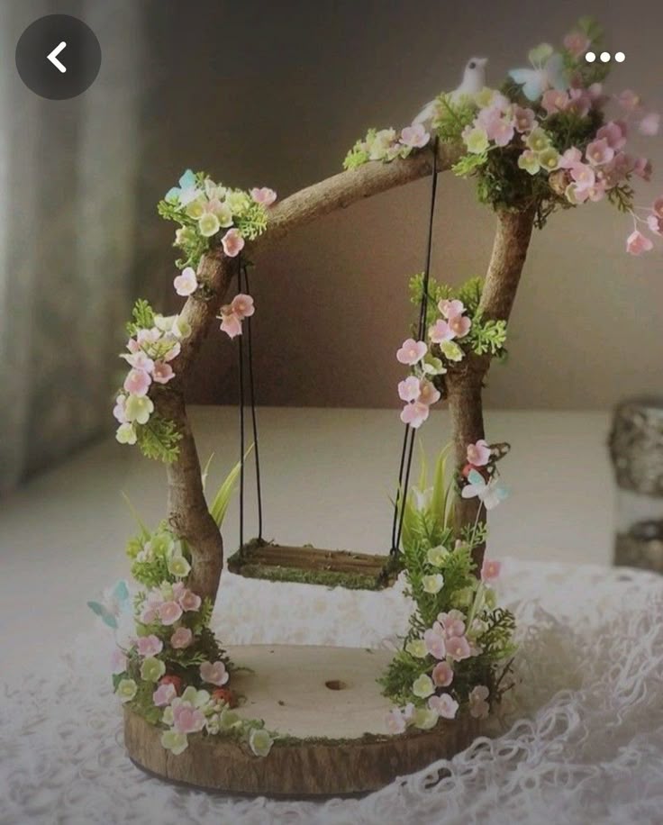 a swing made out of branches with flowers on the bottom and hanging from it's sides