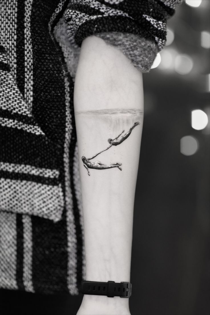 a woman's arm with a small whale tattoo on the left side of her forearm