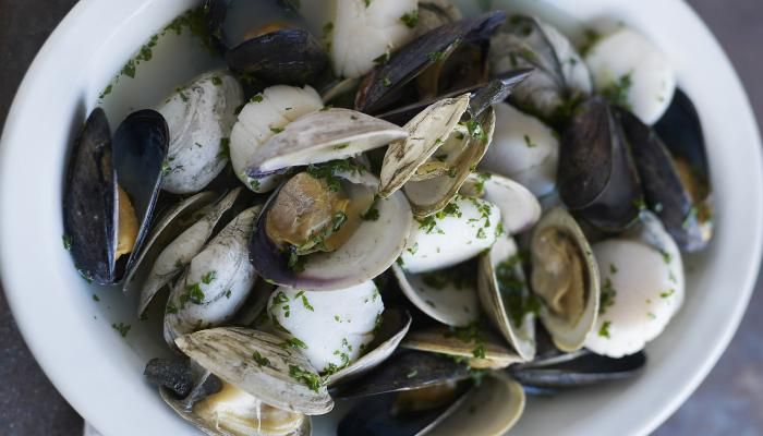 a white bowl filled with clams on top of a table