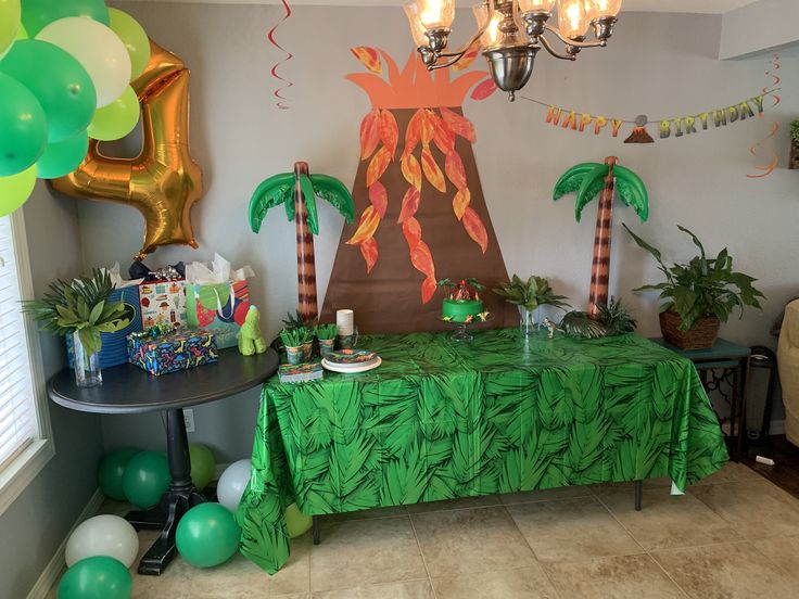 a party table with palm trees and balloons