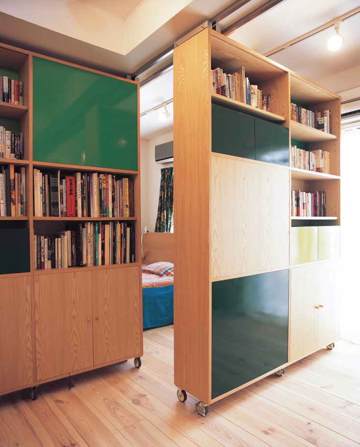 a room with some bookshelves and a bed in the corner next to it