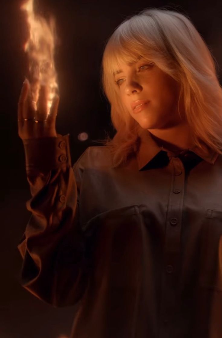 a woman with blonde hair holding a lit object in her hand