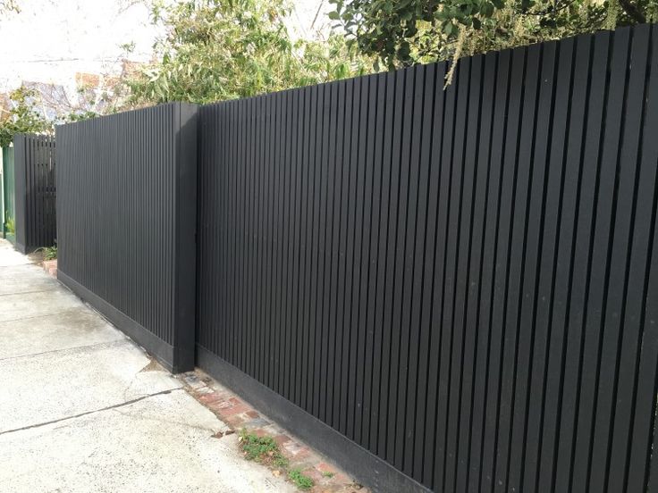 a black fence is next to a sidewalk