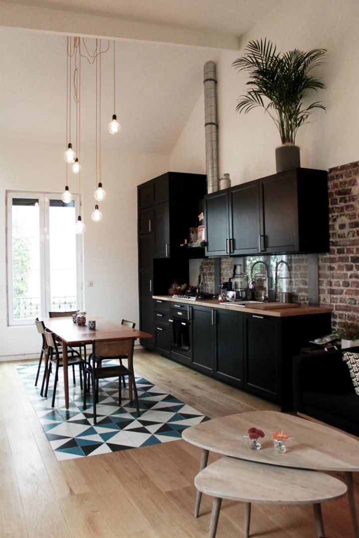 a living room and dining area with wood flooring, black cabinets and white walls