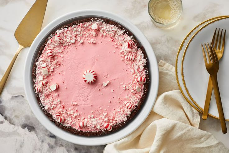 a cake with pink frosting and sprinkles in a white bowl on a table