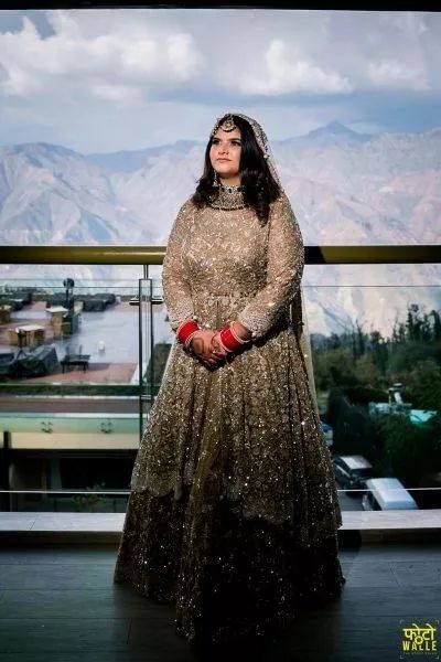 a woman in a long dress standing on a balcony with mountains in the back ground