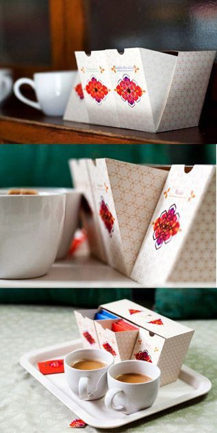 two cups of coffee sit on a plate next to a box with tea in it