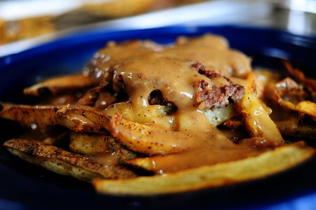 a blue plate topped with french fries covered in gravy