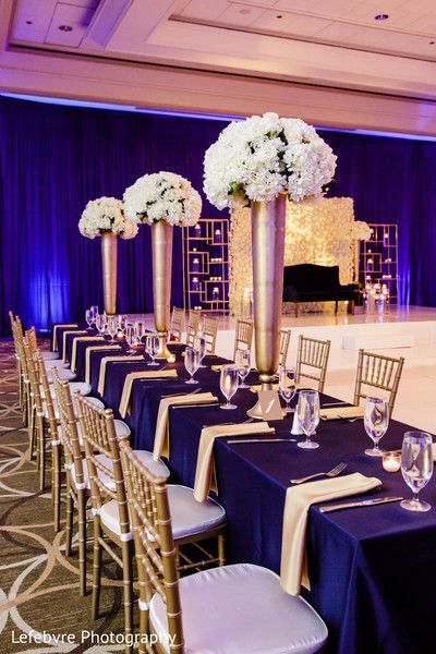 the tables are set with white flowers and gold vases