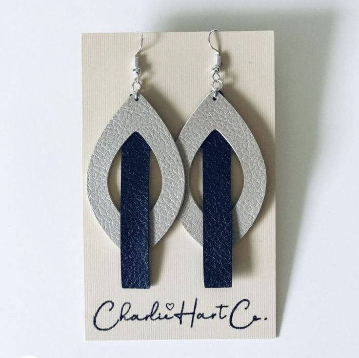 a pair of earrings with blue and white designs on the front, sitting on top of a card