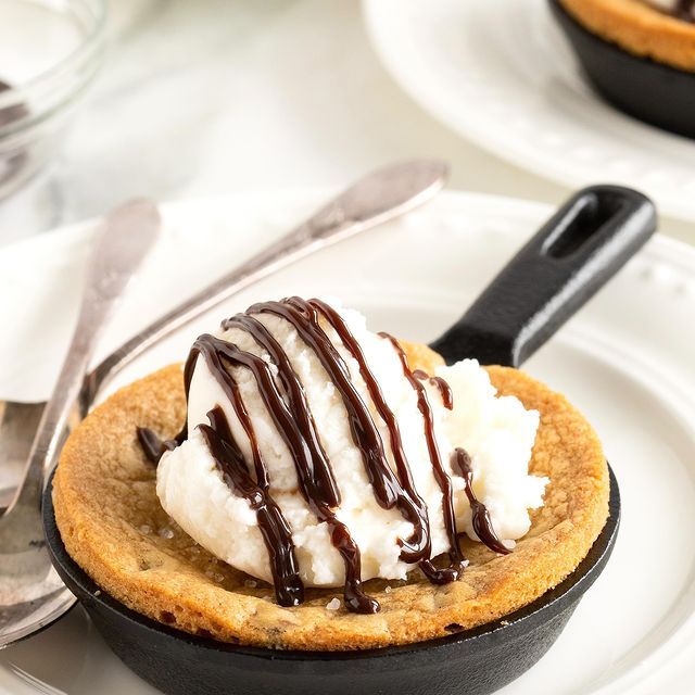 a cookie with ice cream and chocolate drizzled on top sits on a plate