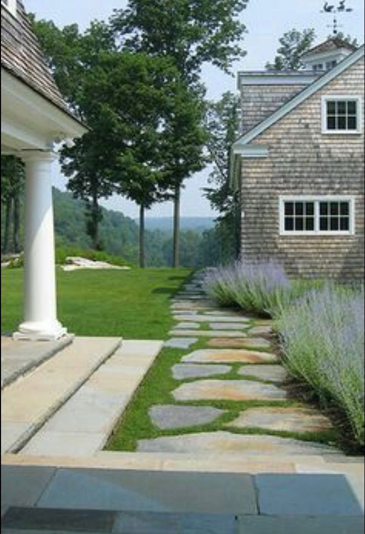 a stone path leading to a house with lavender in the foreground