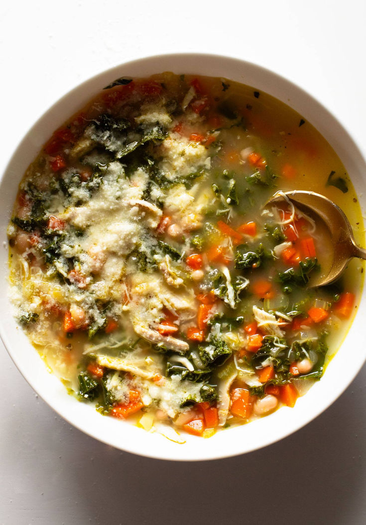 a white bowl filled with soup sitting on top of a table next to a spoon