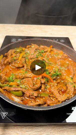 a skillet filled with meat and vegetables on top of a stove