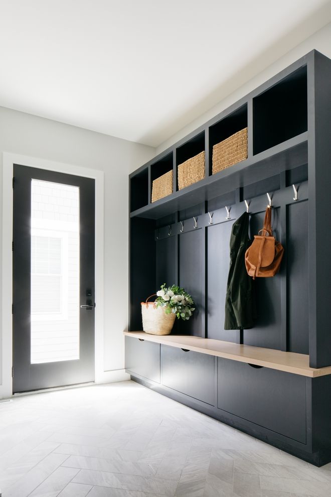 a coat rack with two coats hanging on it's sides, and a plant in the foreground