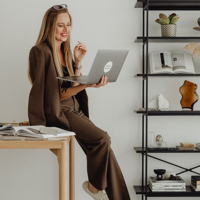 a woman sitting on a desk using a laptop computer