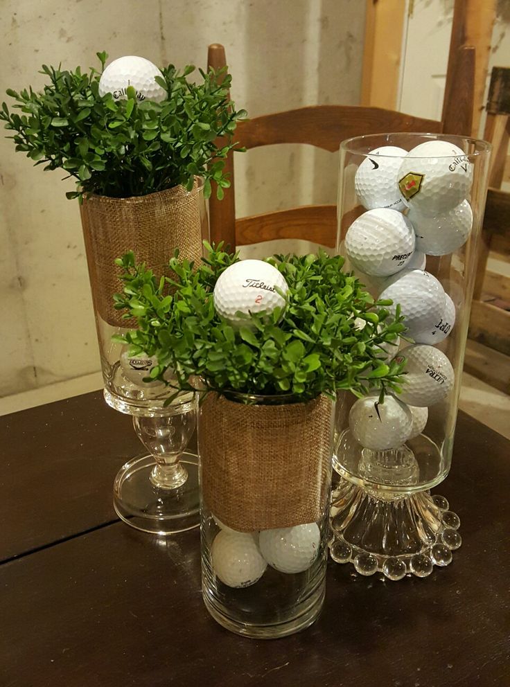 three vases with plants and golf balls in them on top of a wooden table