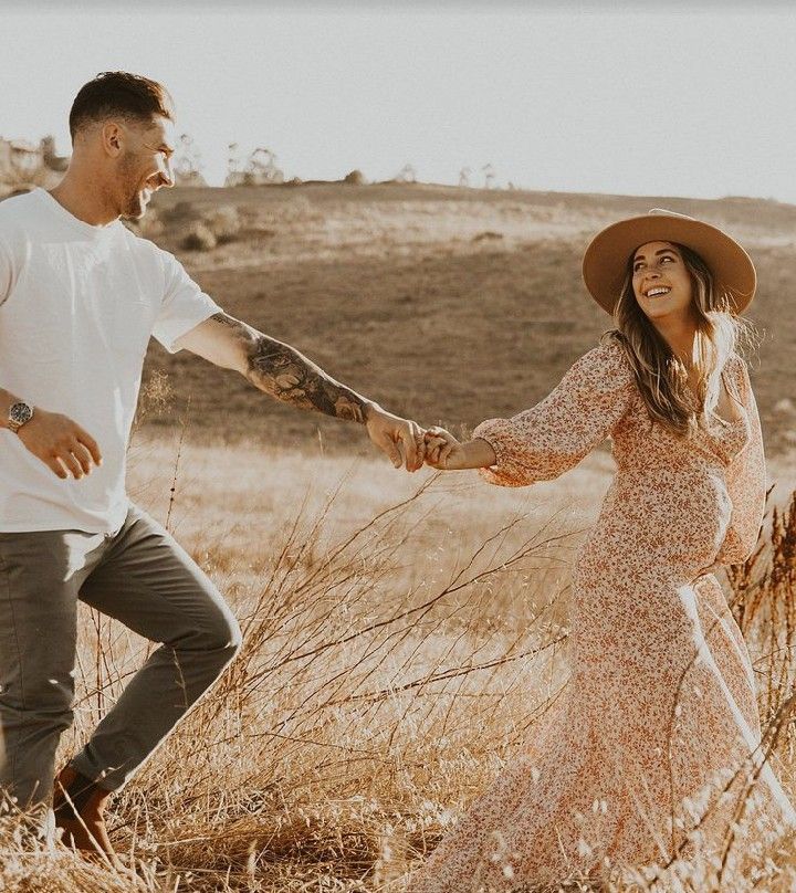 a man and woman holding hands while standing in a field