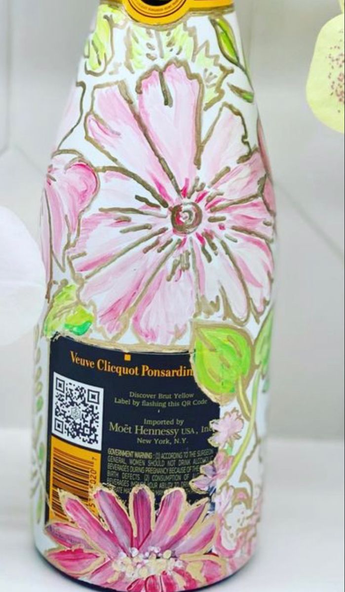 a bottle that is decorated with flowers and has a yellow cap on it's top