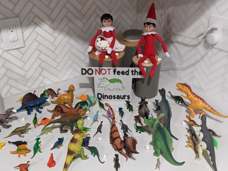 two elfs sitting on top of a trash can filled with dinosaur figurines