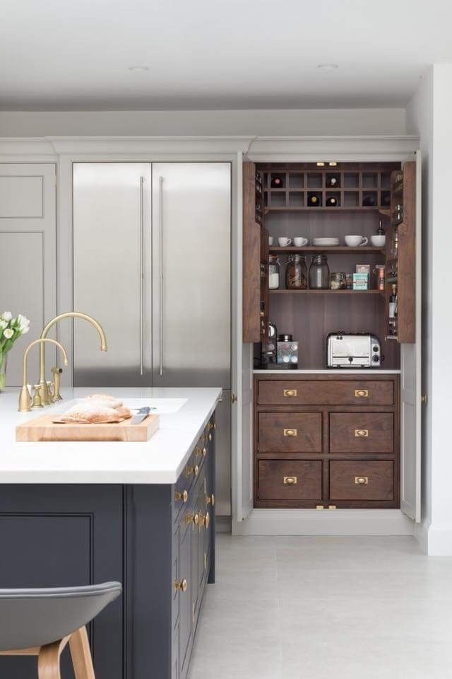 an open cabinet in the middle of a kitchen with white countertops and gray cabinets