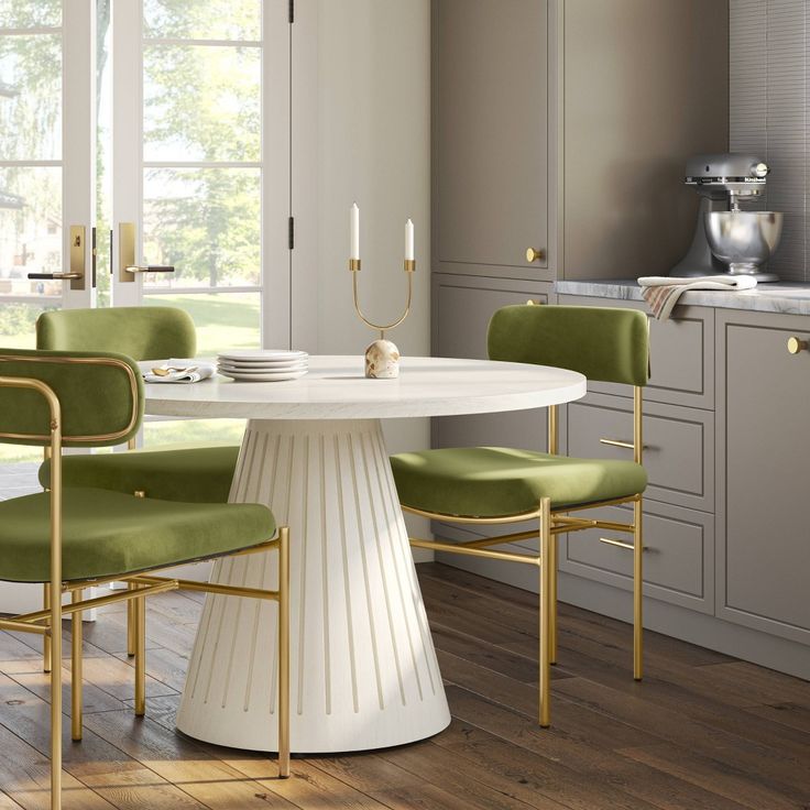 a white table with green chairs around it in the middle of a wooden floored room