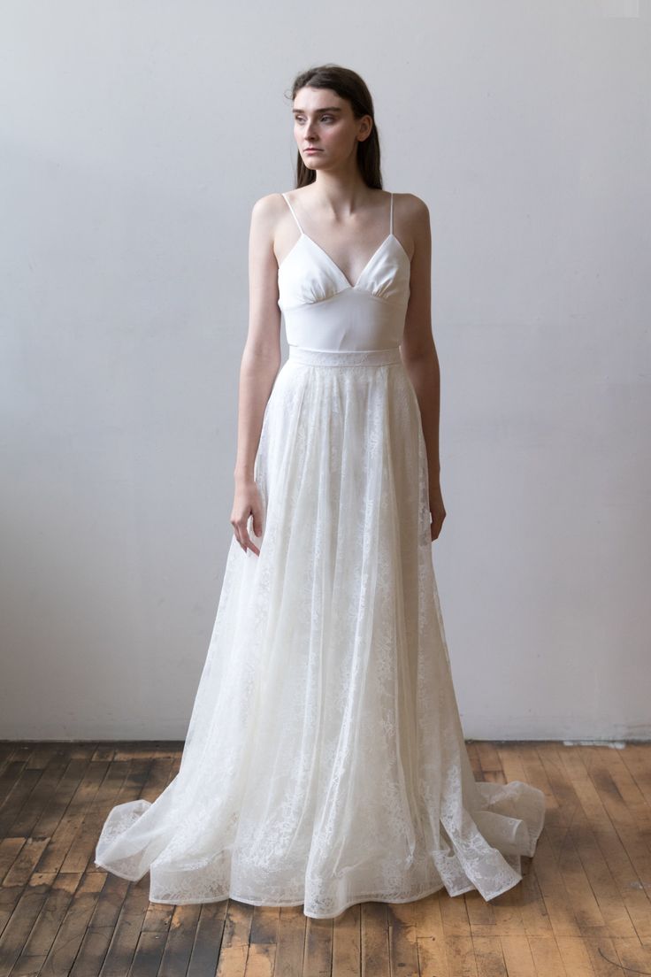 a woman in a white wedding dress standing on a wooden floor with her head turned to the side