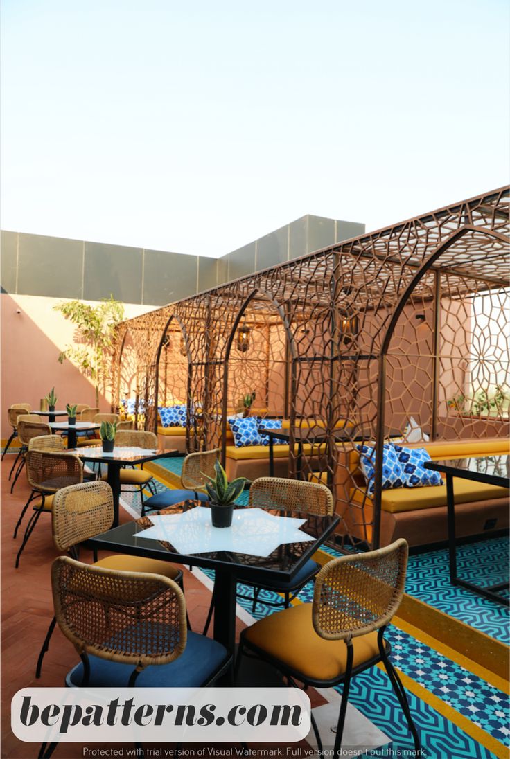 an outdoor seating area with tables and chairs on the floor, under a pergolated roof