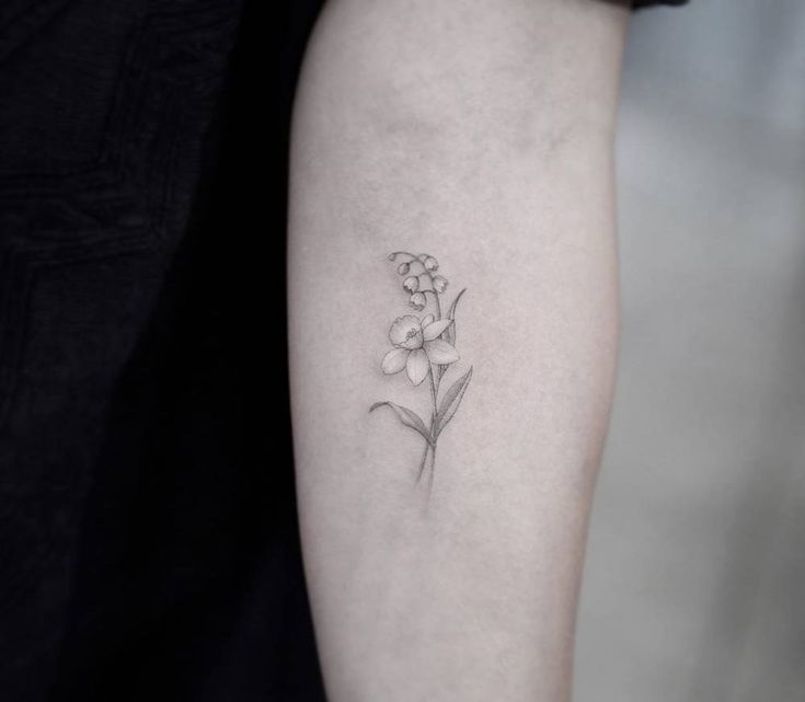 a small flower tattoo on the left arm