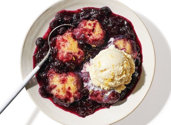 a bowl filled with ice cream and blueberry compote next to a spoon