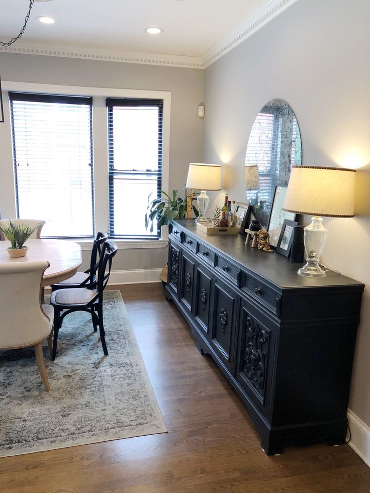 a dining room with a table and chairs next to a large mirror on the wall