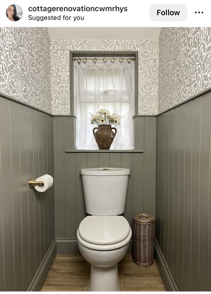 a white toilet sitting in a bathroom next to a window with curtains on the windowsill