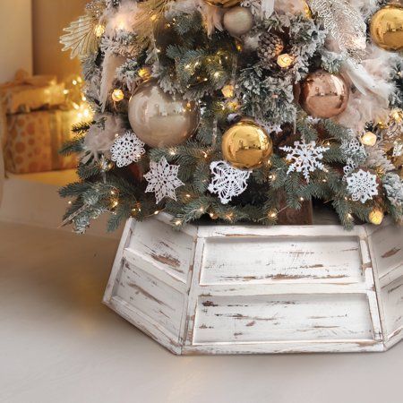 a decorated christmas tree with gold and silver ornaments in a white wooden box on a table