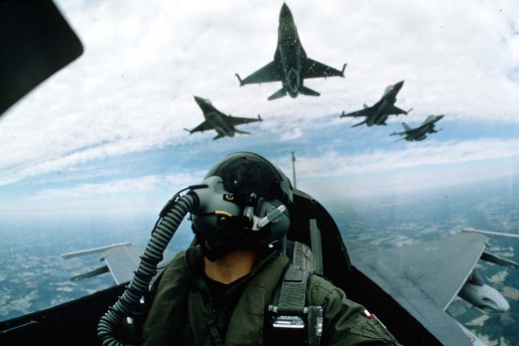 two fighter jets flying in the sky with one pilot looking at the ground below them