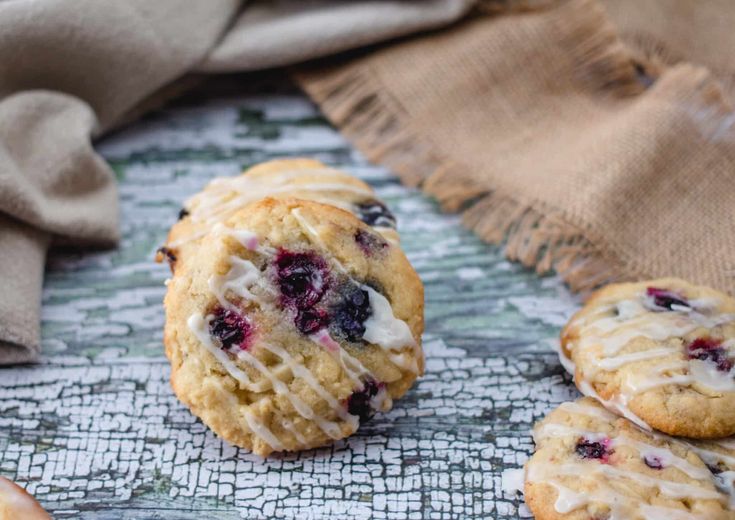 blueberry muffins with icing sitting on a table next to a napkin