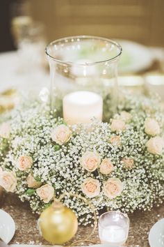 a vase filled with baby's breath flowers on top of a table next to candles