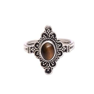 a silver ring with a tiger's eye in the center and filigrees around it