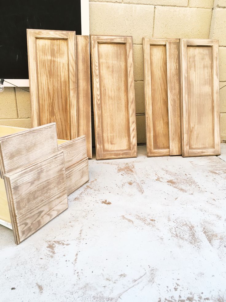 four wooden doors sitting next to each other in front of a chalkboard on the wall